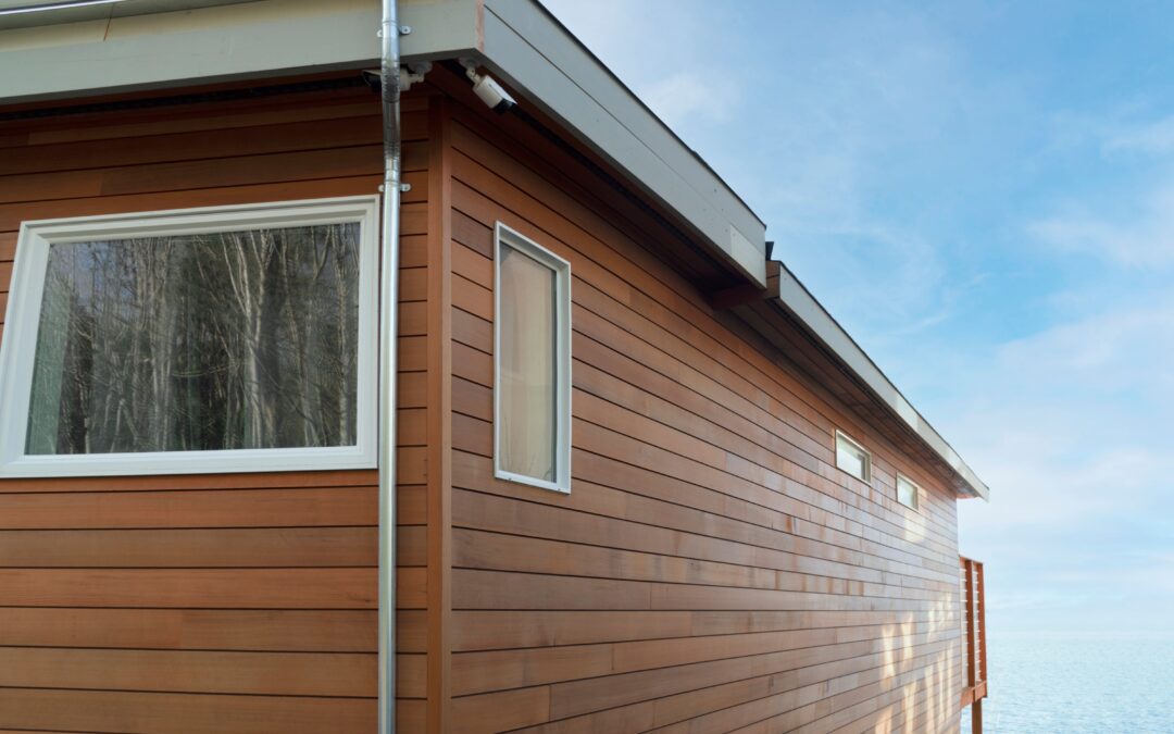 Corner of a wood sided beach house under blue sky.